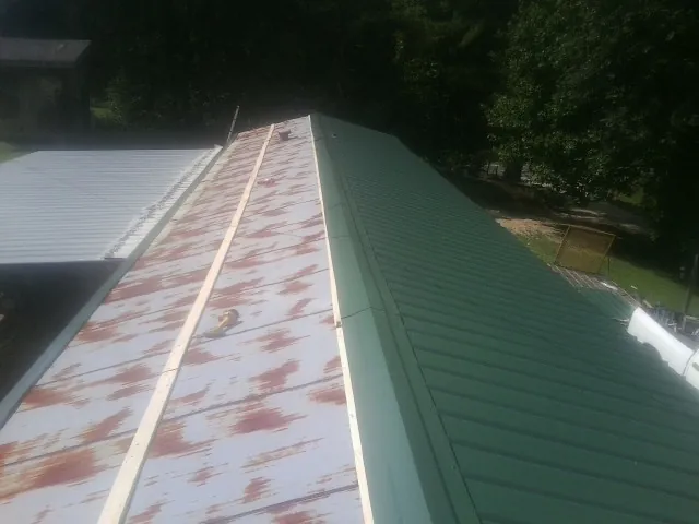 Old rusted panels beside newly installed green metal roofing — Wind Damage Roof Repair by Roofing Brothers in Grandville