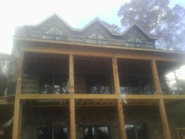 Dormers and porch framing on a large log home under construction — Roof Coating work by our crew in Grandville