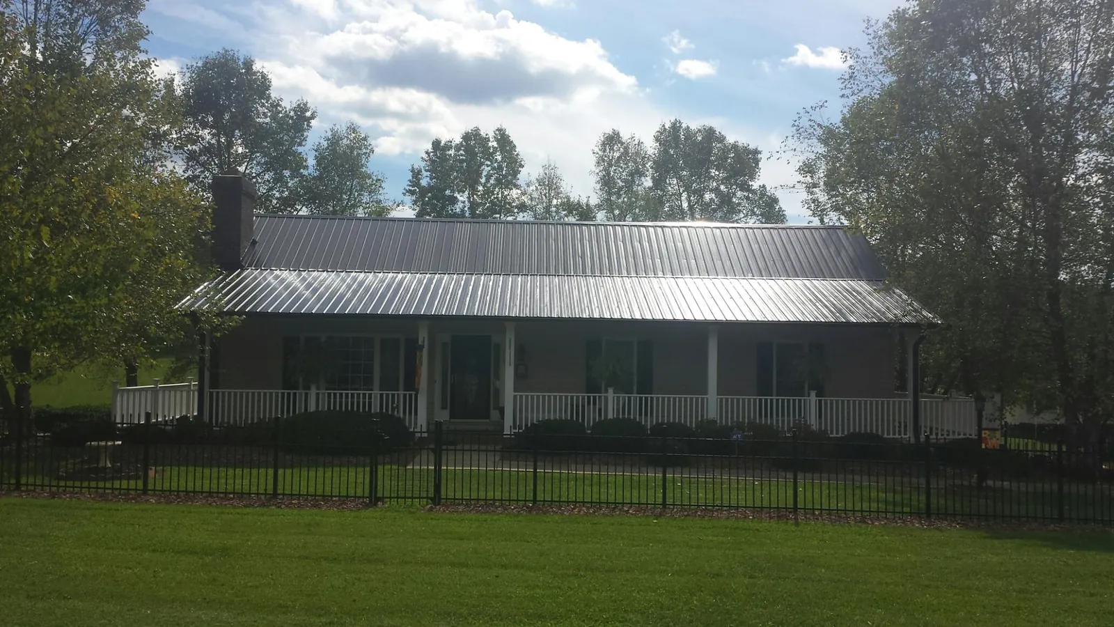 Gray metal roof on a brick ranch with a full width front porch — Gutter Guard Installation work by our crew in Grandville