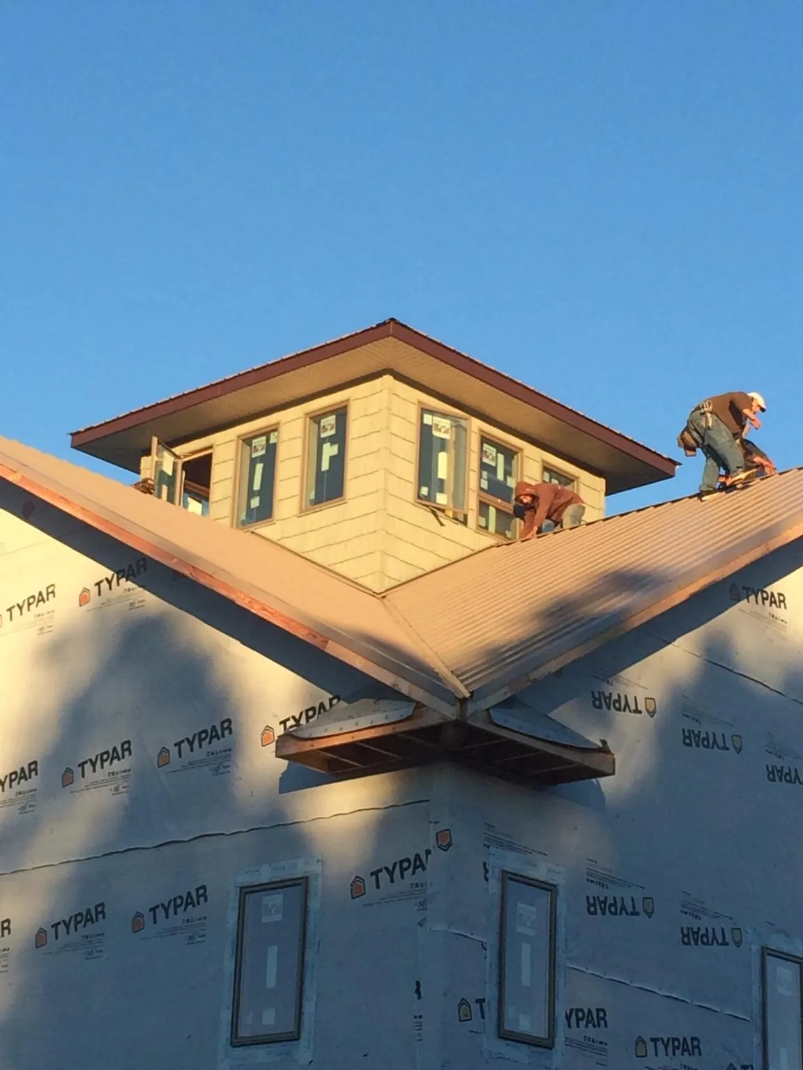Roofers working around a rooftop cupola on a new metal roof at sunset — Roof Waterproofing in Grandville by Roofing Brothers